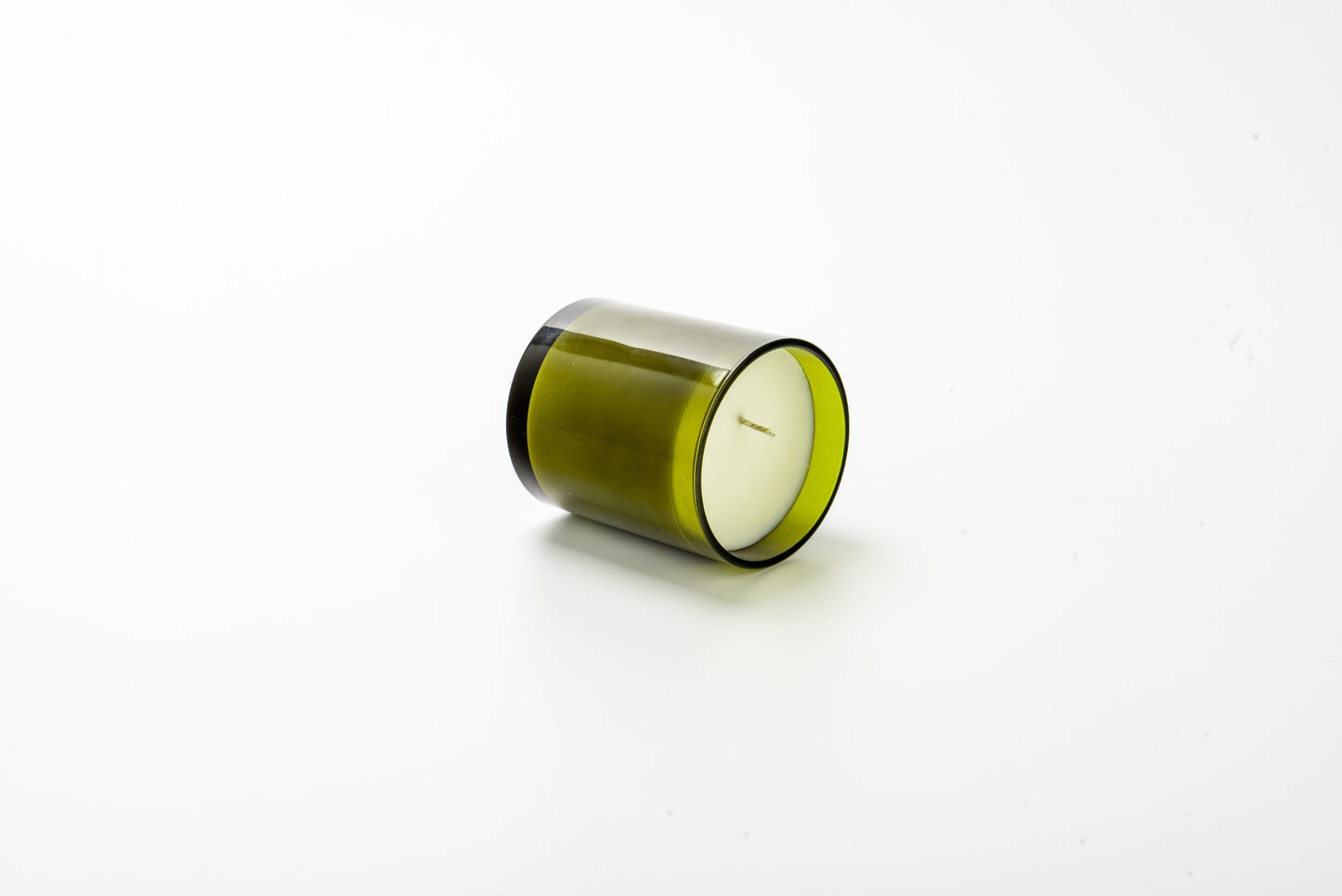 Green candle in a glass container on a white background