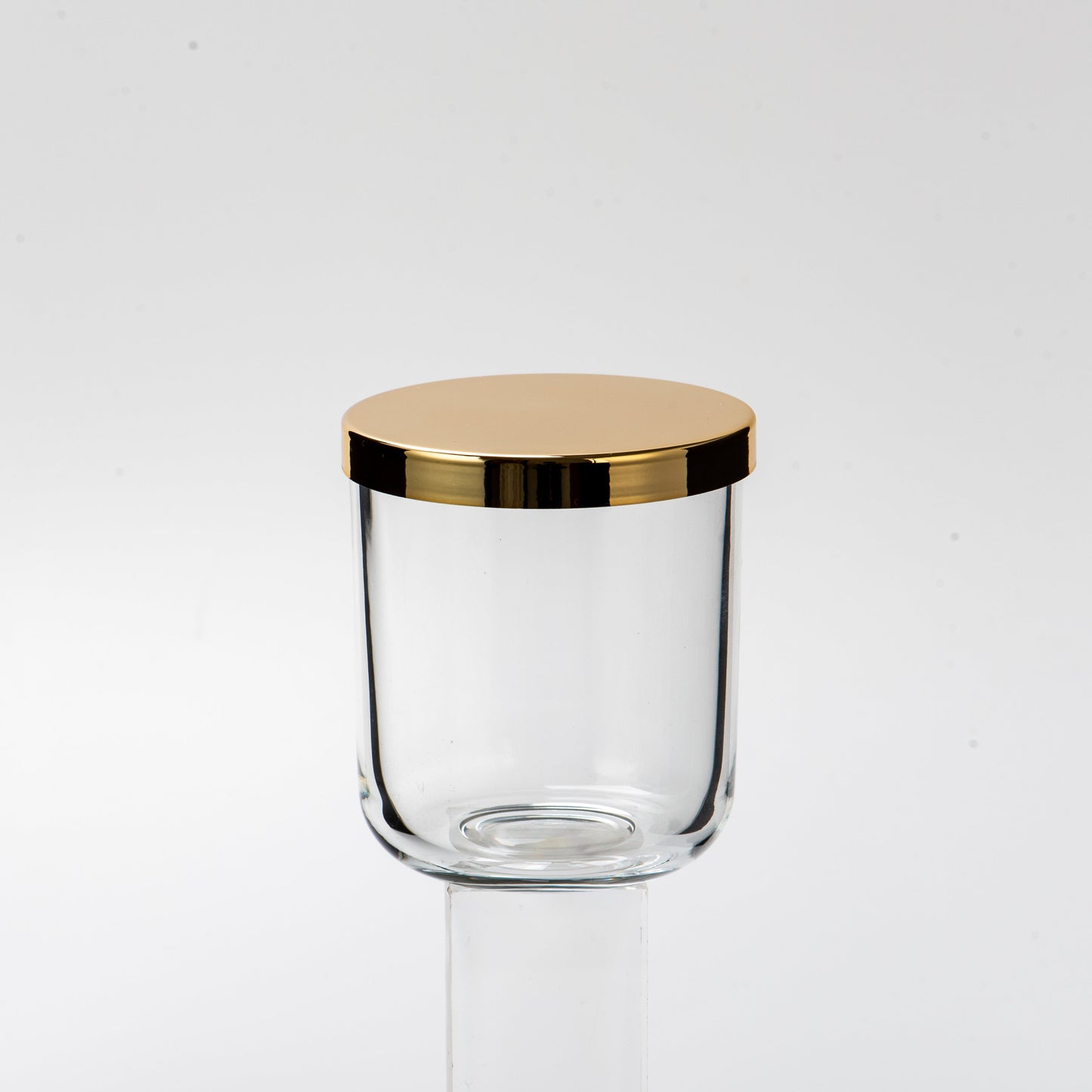 Clear glass jar with a gold lid on a white background