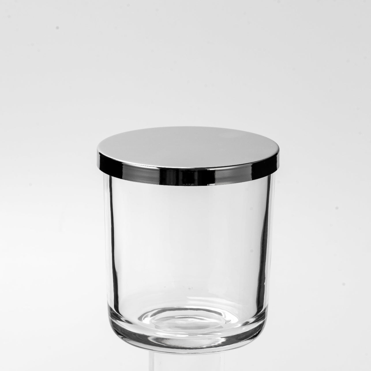 Clear glass container with a metallic lid on a white background