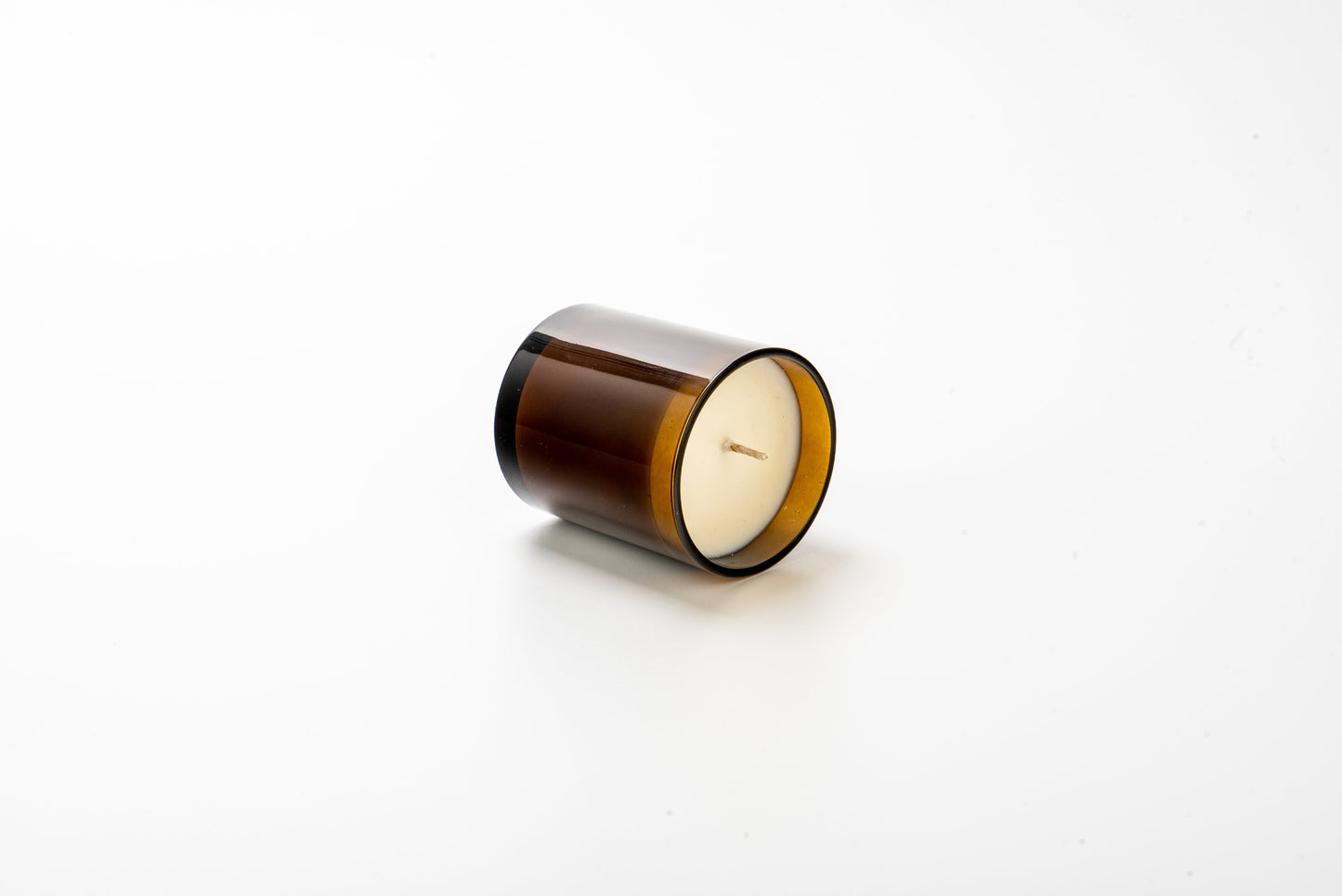Candle in a brown glass holder on a white background