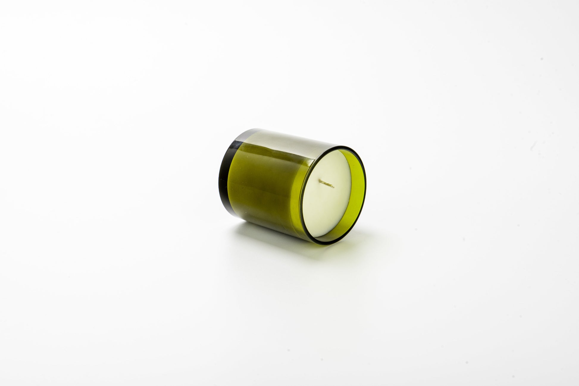 Green candle in a glass container on a white background