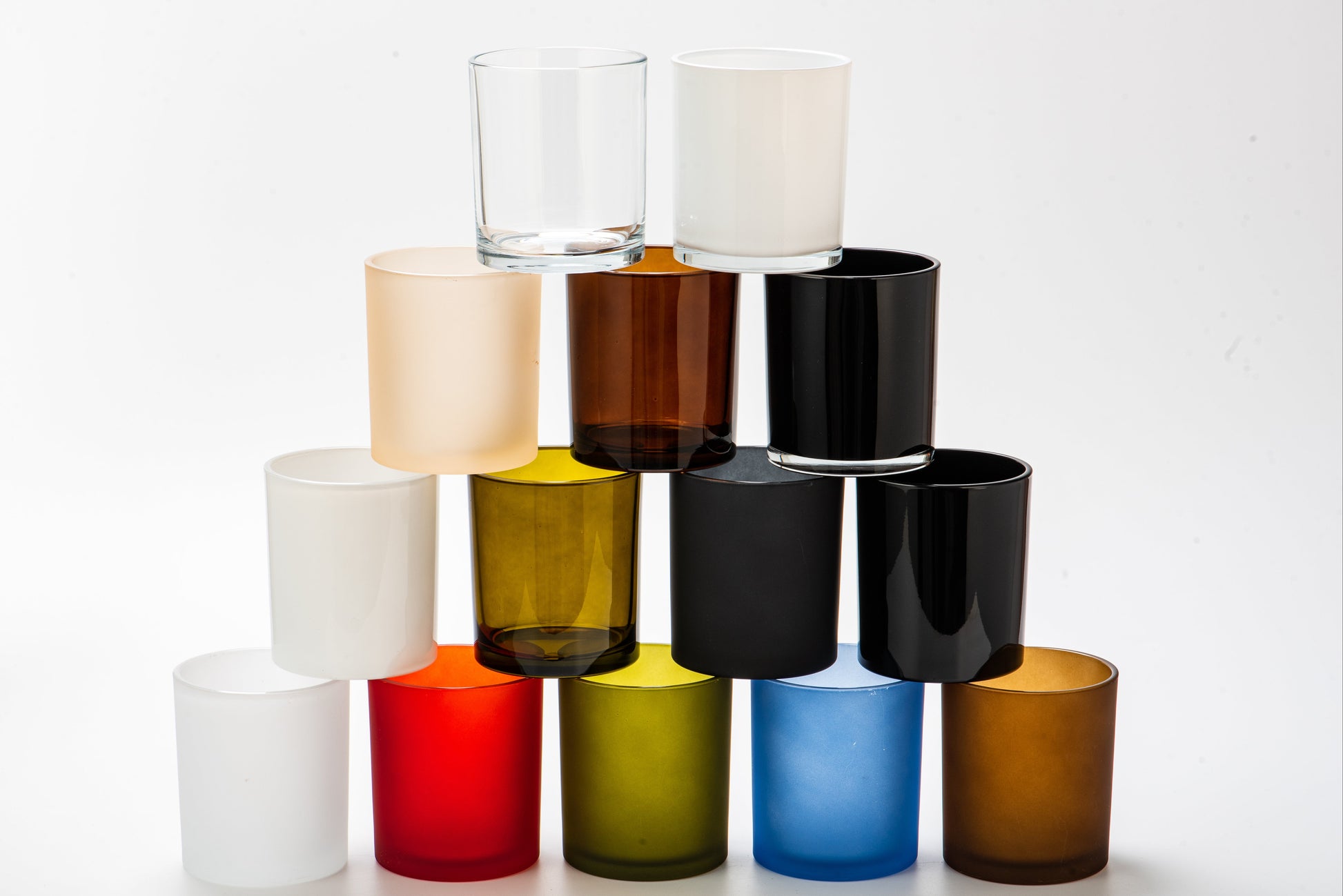 Stack of colorful glass candle holders on a white background