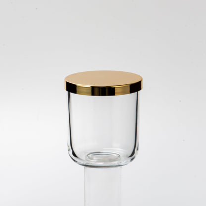 Clear glass jar with a gold lid on a white background