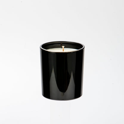Black candle in a white container on a white background