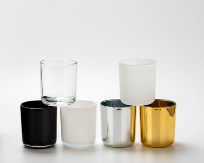Set of six glass tumblers in black, clear, white, and gold on a white background